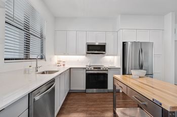 a kitchen with white cabinets and stainless steel appliances and a wooden counter top at Odyssey, Florida